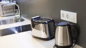 Un rincón cocina con un tostador, un hervidor y un lavamanos.