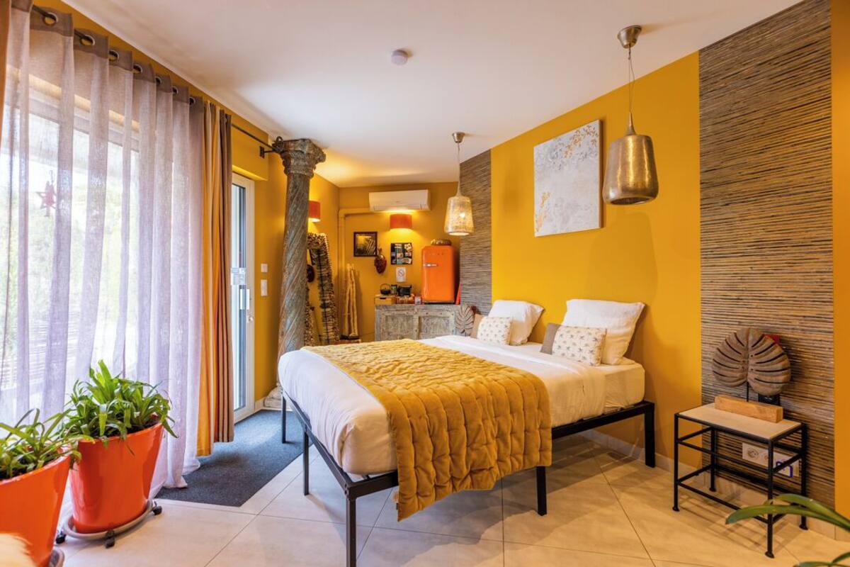 Une chambre à coucher avec un lit, une table de chevet, une plante en pot et une vue sur l’ext érieur.