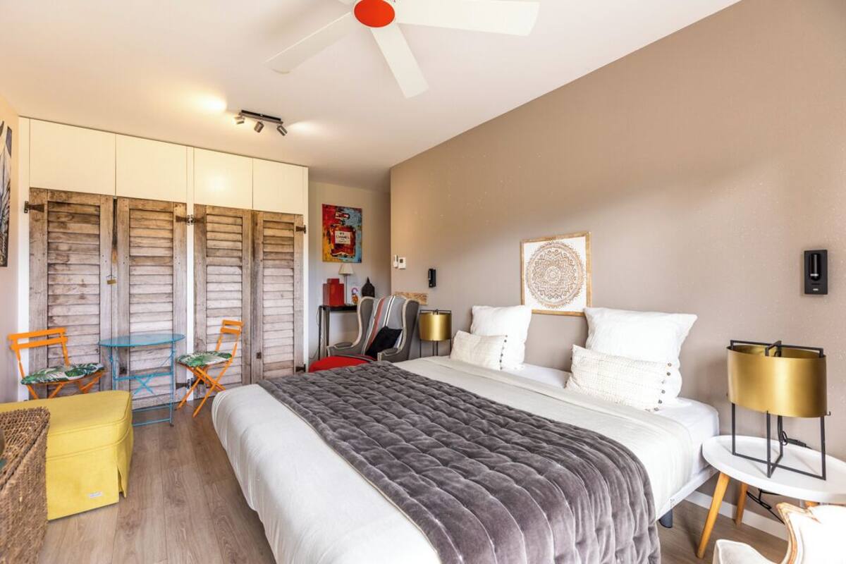 Une chambre à coucher comprenant un lit, un ventilateur de plafond, une armoire, une table et des chaises.