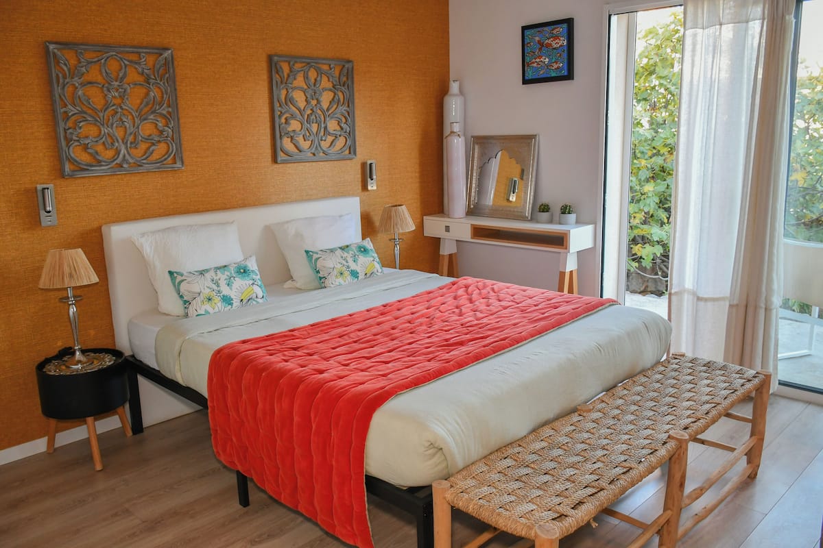 Une chambre à coucher comprenant un lit, un banc, une table de chevet et une commode.