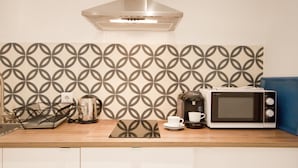A kitchenette with a microwave, coffee maker, and a patterned backsplash. - A perfect refuge in Madrid's city center (Madrid)
