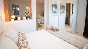 A bedroom with a bed, a bedside table, a mirror, a wardrobe, and a door leading to another room. - A perfect refuge in Madrid's city center (Madrid)