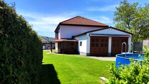 A two-story house with a red-tiled roof, a garage, and a swimming pool.