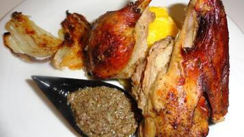 A plate with roasted chicken, lemon slices, and a sauce.