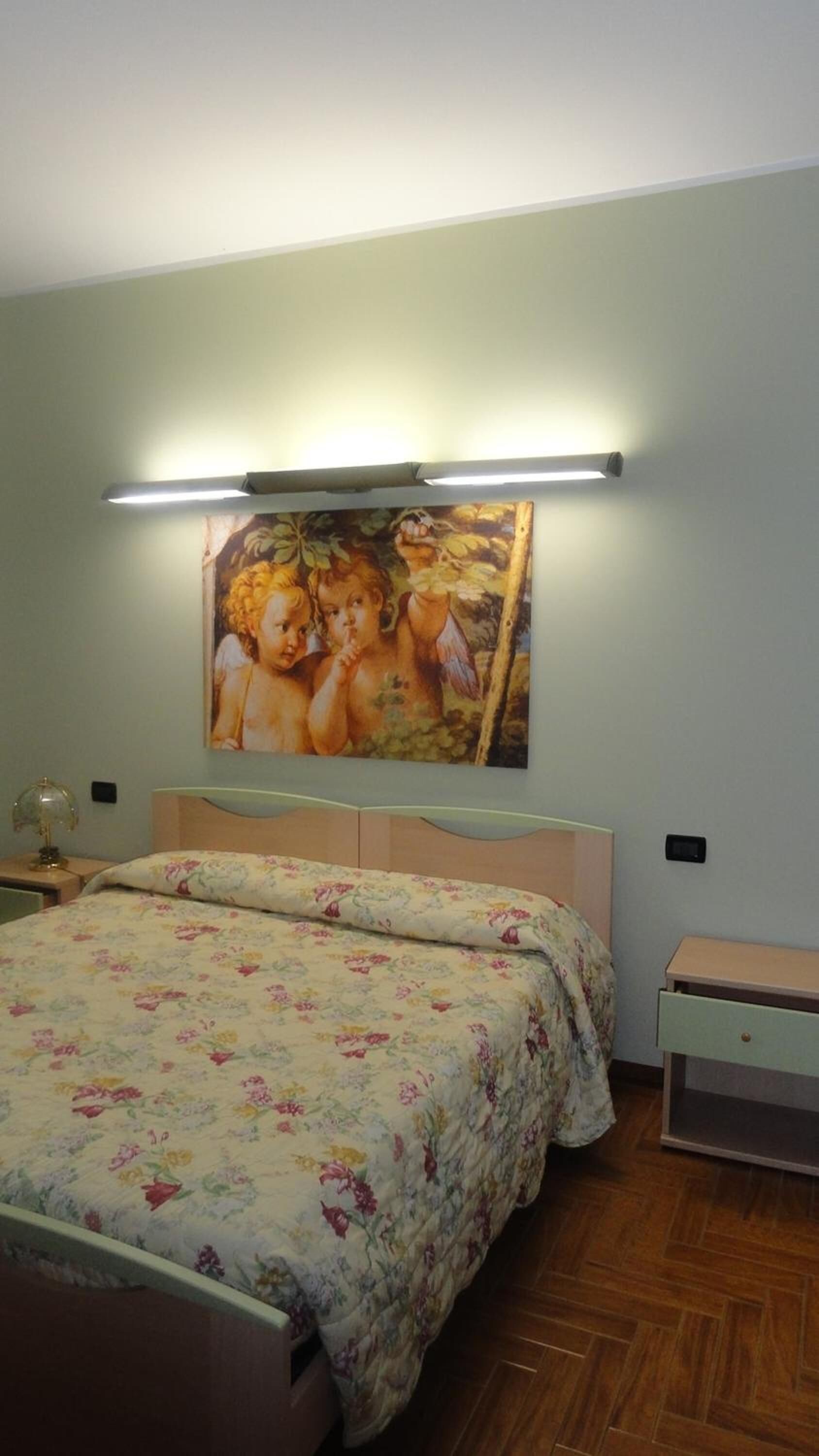 Un dormitorio con cama, mesita de noche y lámpara de pared.