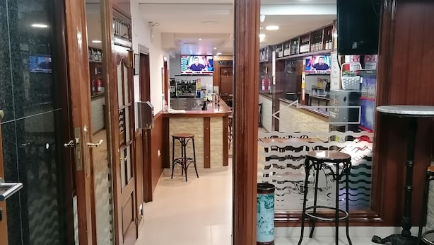 A hotel lobby with a reception desk, seating area, and a bar. - Hostal Adelia (A Coruña)