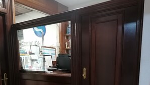 A reception area with a wooden door, a reception desk, and a tiled floor. - Hostal Adelia (A Coruña)
