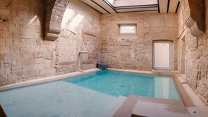 Piscina coberta com paredes de pedra, uma pequena janela e porta.