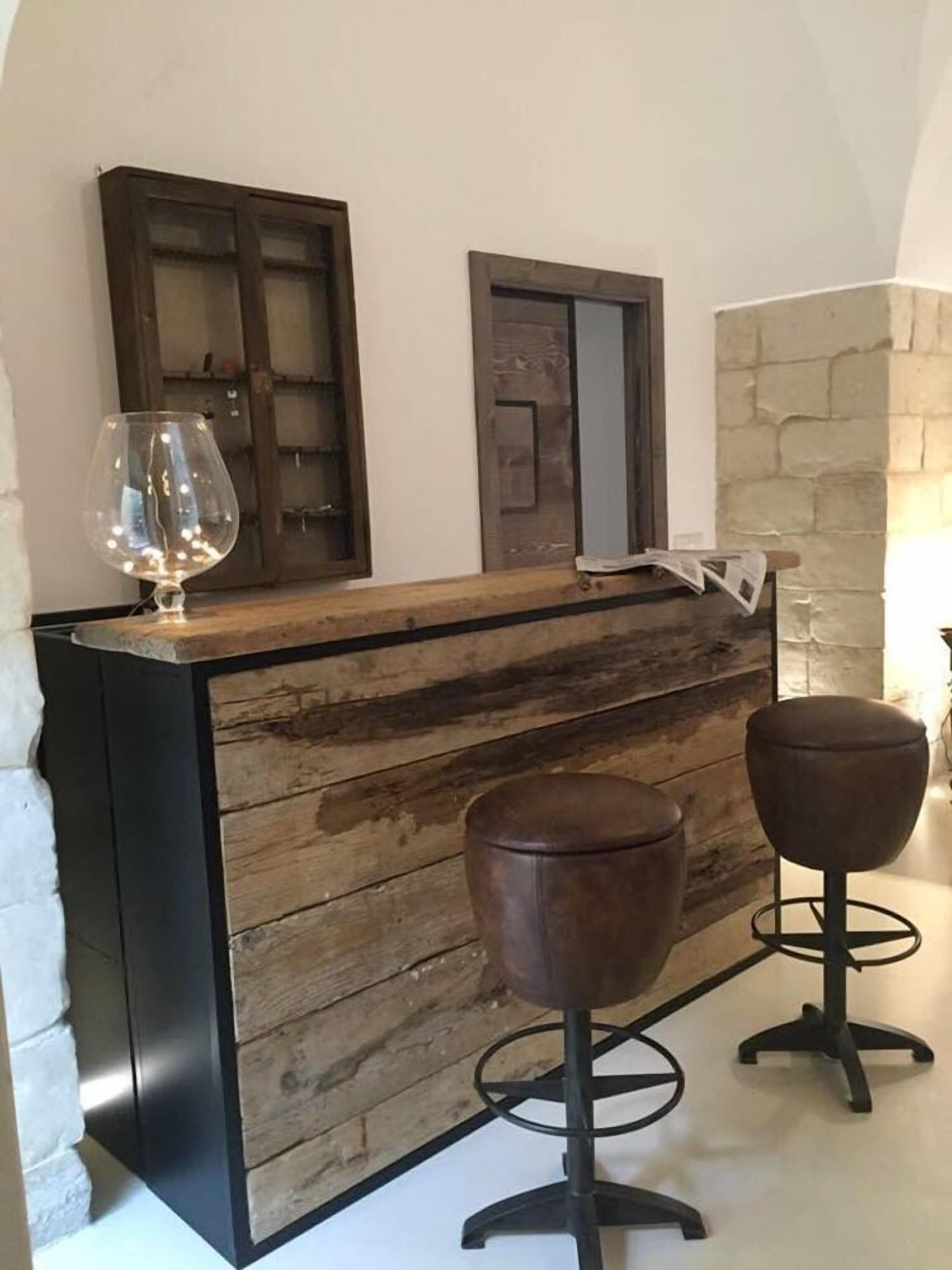 A reception desk with a wooden finish, two bar stools, and a wine glass on the counter.
