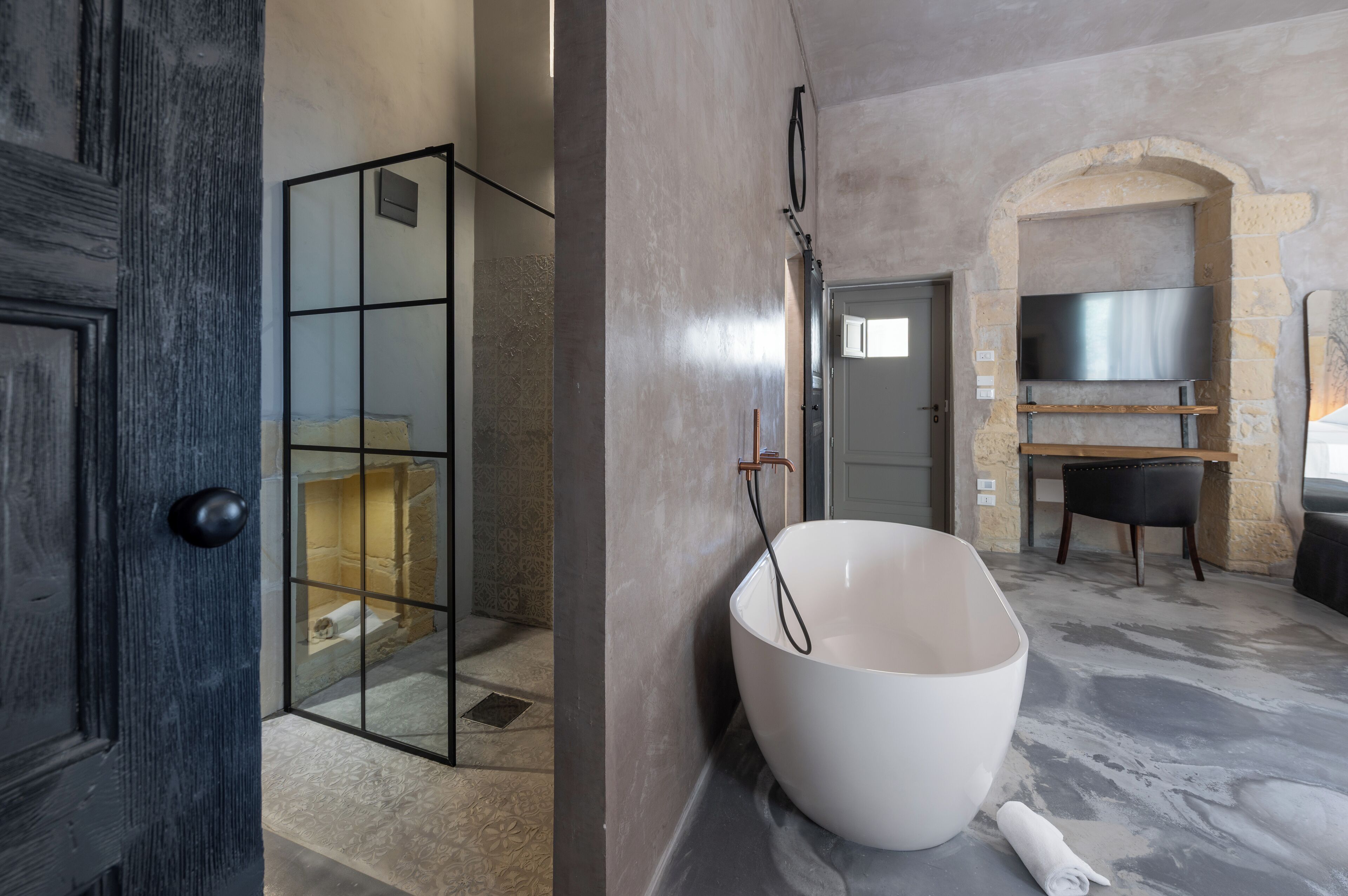 Een moderne badkamer met een glazen douche, een groot wit wastafel en een boog van steen.