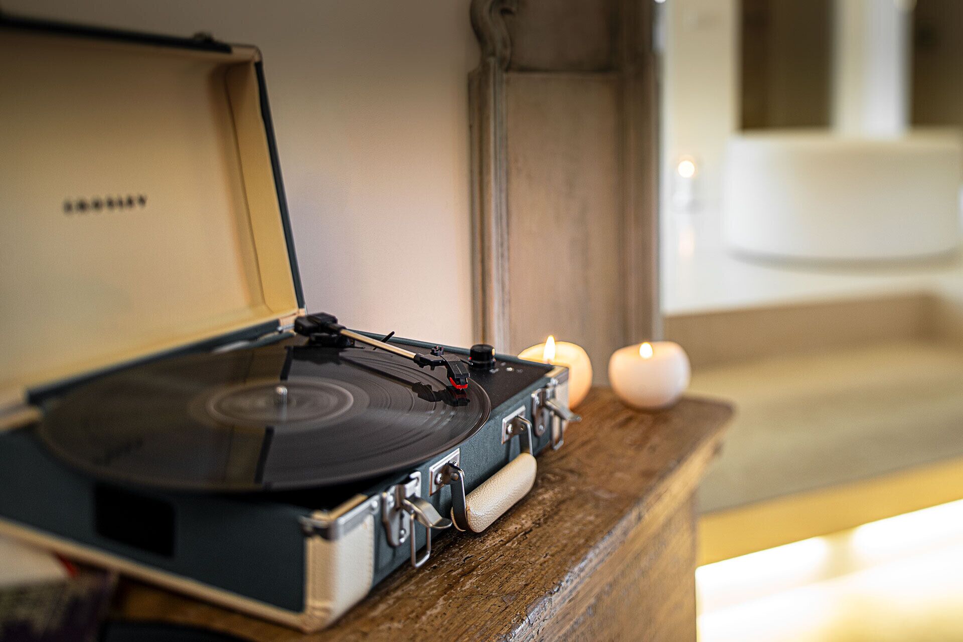 A turntable on a wooden surface with a candle in the background.