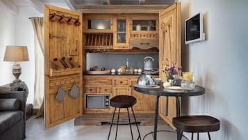 A compact kitchen with wooden cabinets, a built-in microwave, and a small dining area with stools.
