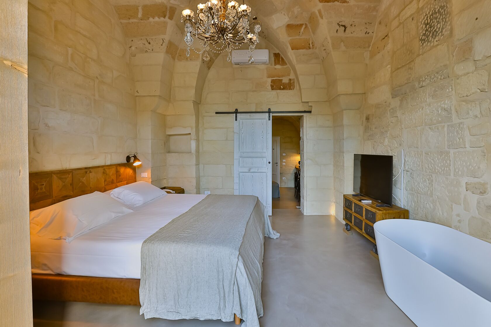 Ein Schlafzimmer mit einem großen Bett, einer weißen Badewanne und einem Kronleuchter.