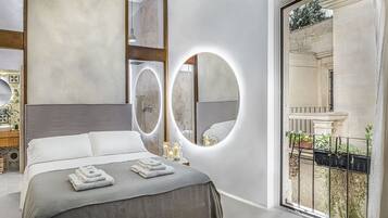 Un dormitorio moderno con una cama grande, dos espejos, un tocador con lavabo y un balcón con plantas.