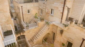A courtyard with stone buildings, a central staircase, and potted plants.