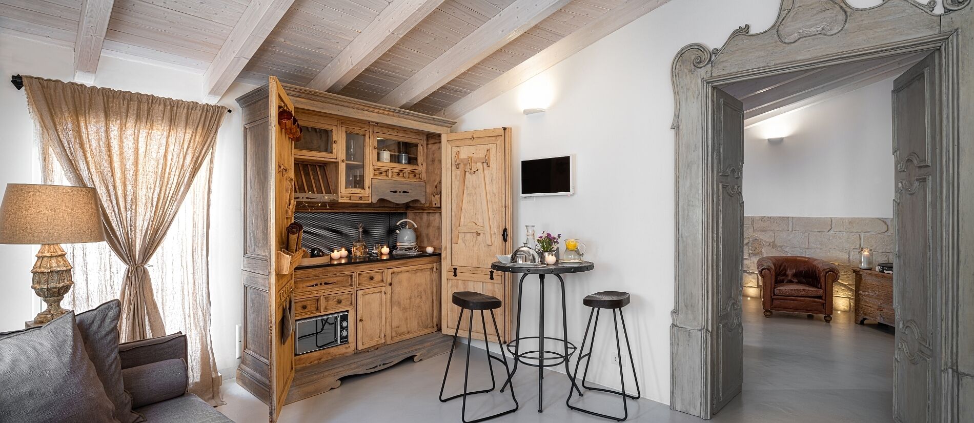 A rustic kitchen with wooden cabinets, a built-in stove, and two bar stools.