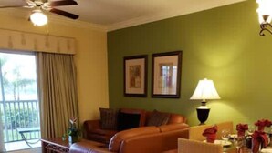 A living room with a brown sofa, a dining table set for two, and a ceiling fan. - Chelsea's Villa (Kissimmee)