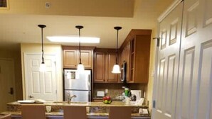 A kitchen with three chairs, a refrigerator, and a microwave. - Chelsea's Villa (Kissimmee)