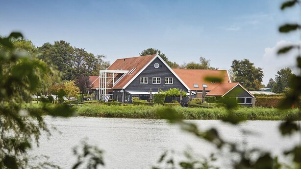 A house with a sloped roof, a balcony, and a view of a body of water.