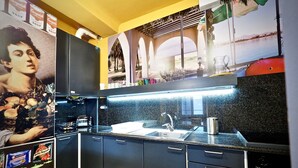 A modern kitchen with black cabinets, a stainless steel sink, and a black countertop. - Lussuosa Dimora San Lorenzo (Genoa)