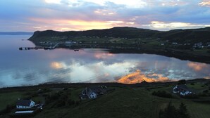 A coastal landscape with a calm lake, a pier, and scattered houses. - Old Pier Cottage B&B (Uig)