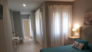 Un dormitorio con cama, escritorio y mesita de noche.