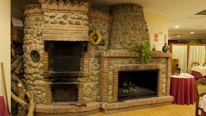 Una chimenea de piedra con revestimiento de ladrillo, un espacio para guardar leña de madera y un adorno circular en la pared.