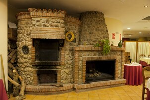 Una chimenea de piedra con revestimiento de ladrillo, un espacio para guardar leña de madera y un adorno circular en la pared.