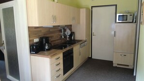 A compact kitchen with wooden cabinets, a coffee maker, a microwave, and a dishwasher.