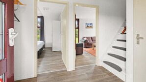 Una habitación de hotel moderna con piso de madera, una cama, un sofá y una escalera.
