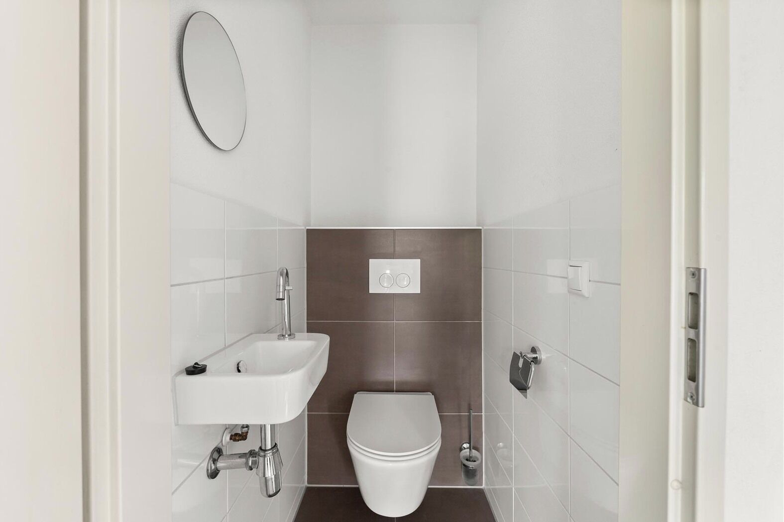 A small, modern bathroom with a white sink, a toilet, and a mirror.