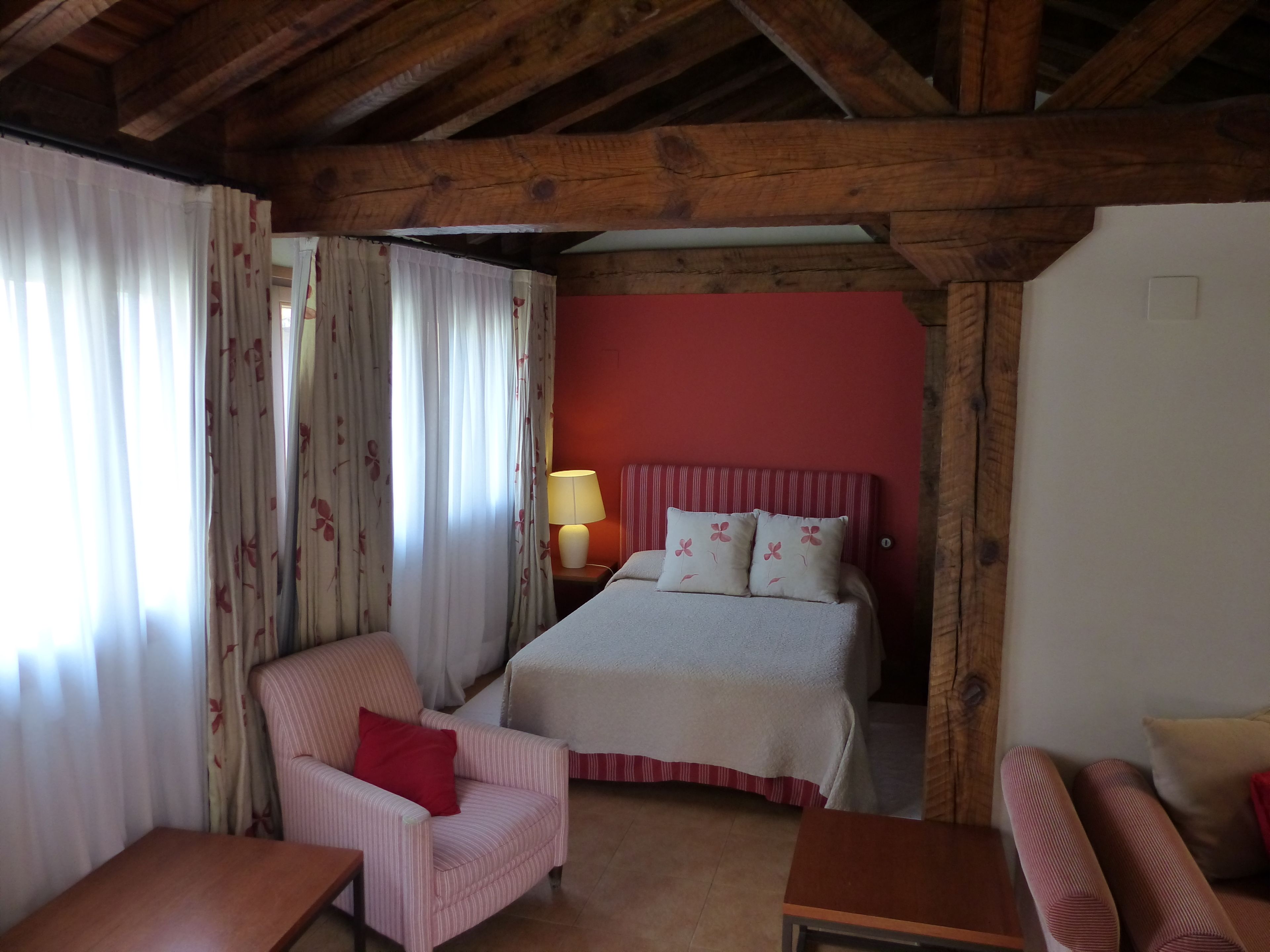 Una habitación con cama, silla, mesa y lámpara.