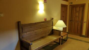 A wooden bench with a table lamp, a sign indicating a public toilet, and a door with the number 22.