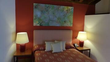 A hotel room with a bed, two bedside tables with lamps, a telephone, and a painting on the wall.