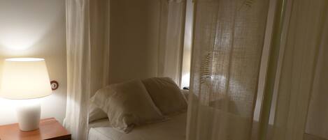 A bed with a canopy, a bedside table with a lamp, and a wall clock.