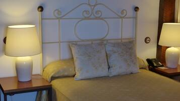 Una habitación de hotel con una cama, dos lámparas de noche, un teléfono y un reloj de pared.