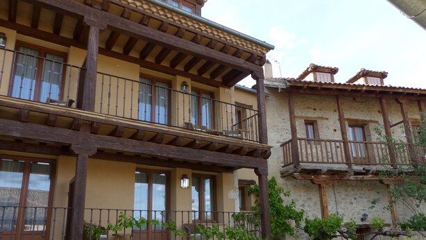 Un edificio tradicional con balcón, paredes de piedra y vigas de madera.