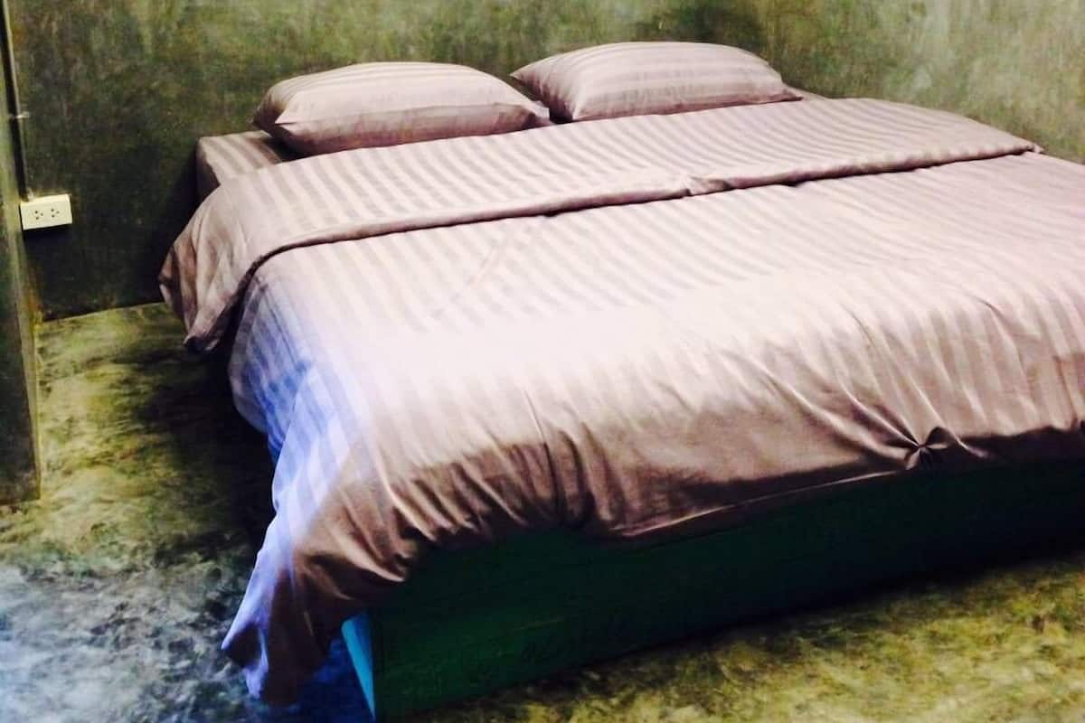 Una cama con estructura verde y ropa de cama morada en una habitación con paredes verdes con textura.