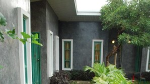 A narrow pathway with stepping stones leading to a building with green-framed windows and a grey exterior. - Chatchanan Resort (Mae Sot)