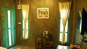 A room with two green doors, a table with two stools, a framed picture on the wall, and a television on the right. - Chatchanan Resort (Mae Sot)