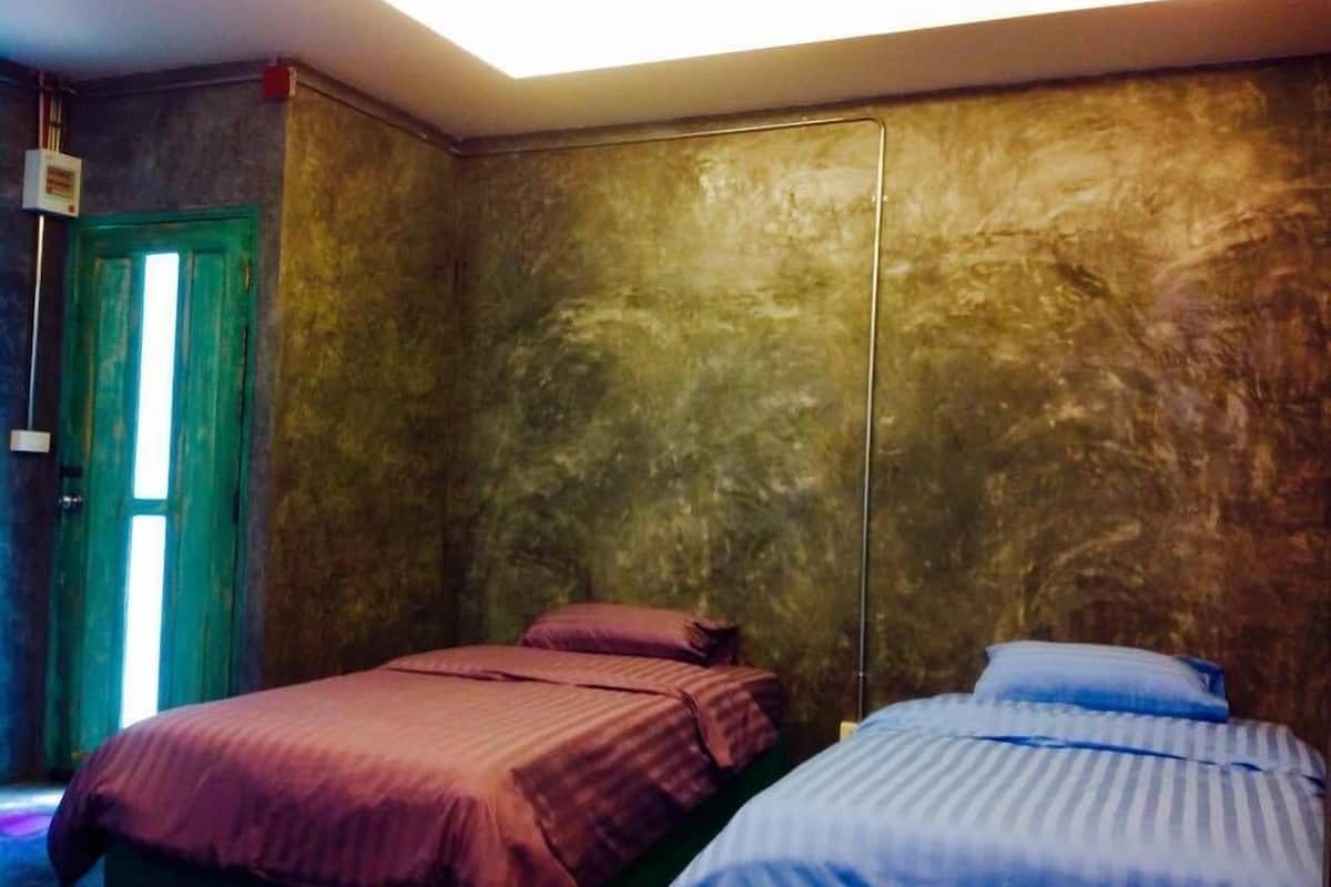Una habitación con dos camas, una con cubrecama rosa y la otra con cubrecama azul.