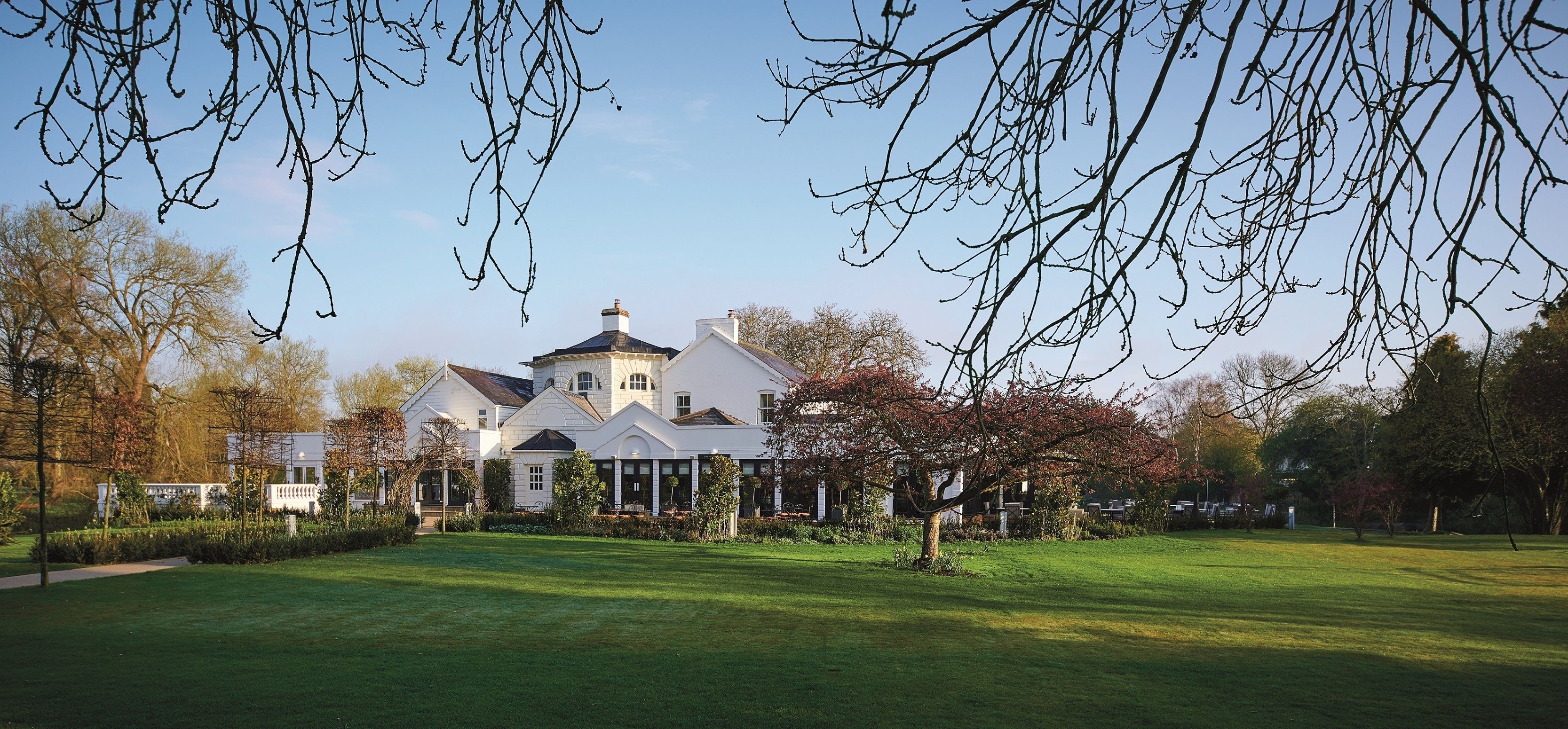 A large, white, two-story house with a symmetrical facade, a central tower, and a well-maintained lawn.