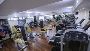 Una palestra con diverse attrezzature per esercizi, tra cui tapis roulant, macchinari per pesi e una macchina per esercizi alle gambe da seduti.