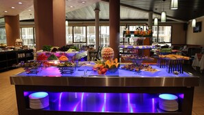 Un tavolo da buffet con diversi cibi e una decorazione centrale a forma di ananas.