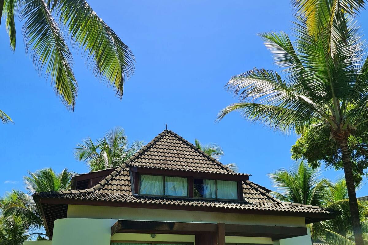 A two-story building with a tiled roof, large windows, and a grassy lawn.