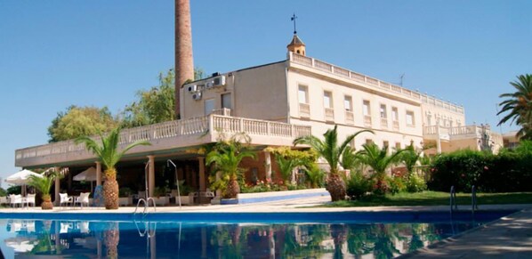 A large building with a pool, palm trees, and a clear sky. - Hotel Las Navas (Malagon)