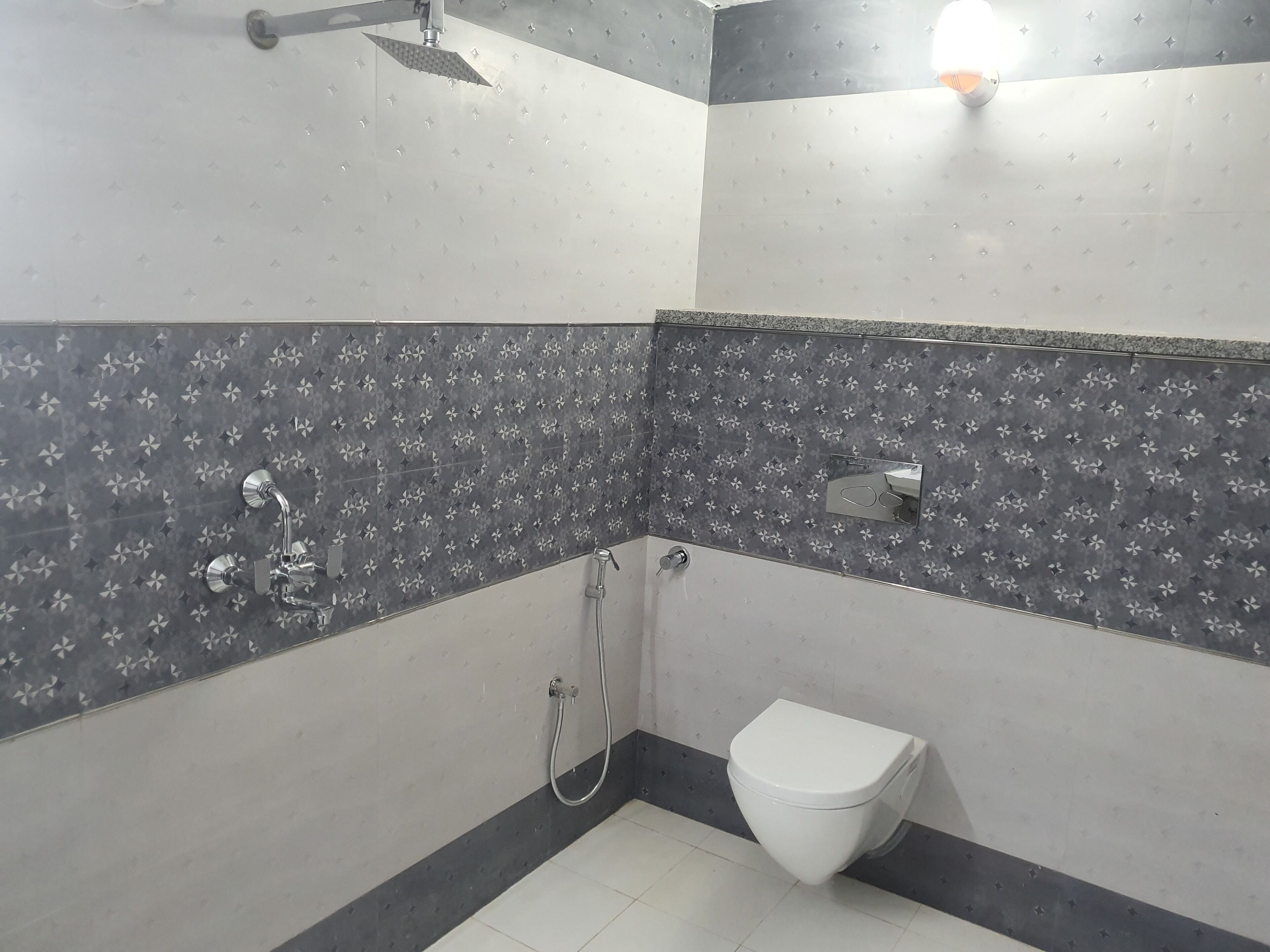 A bathroom with a toilet, a shower, and a wall-mounted faucet.