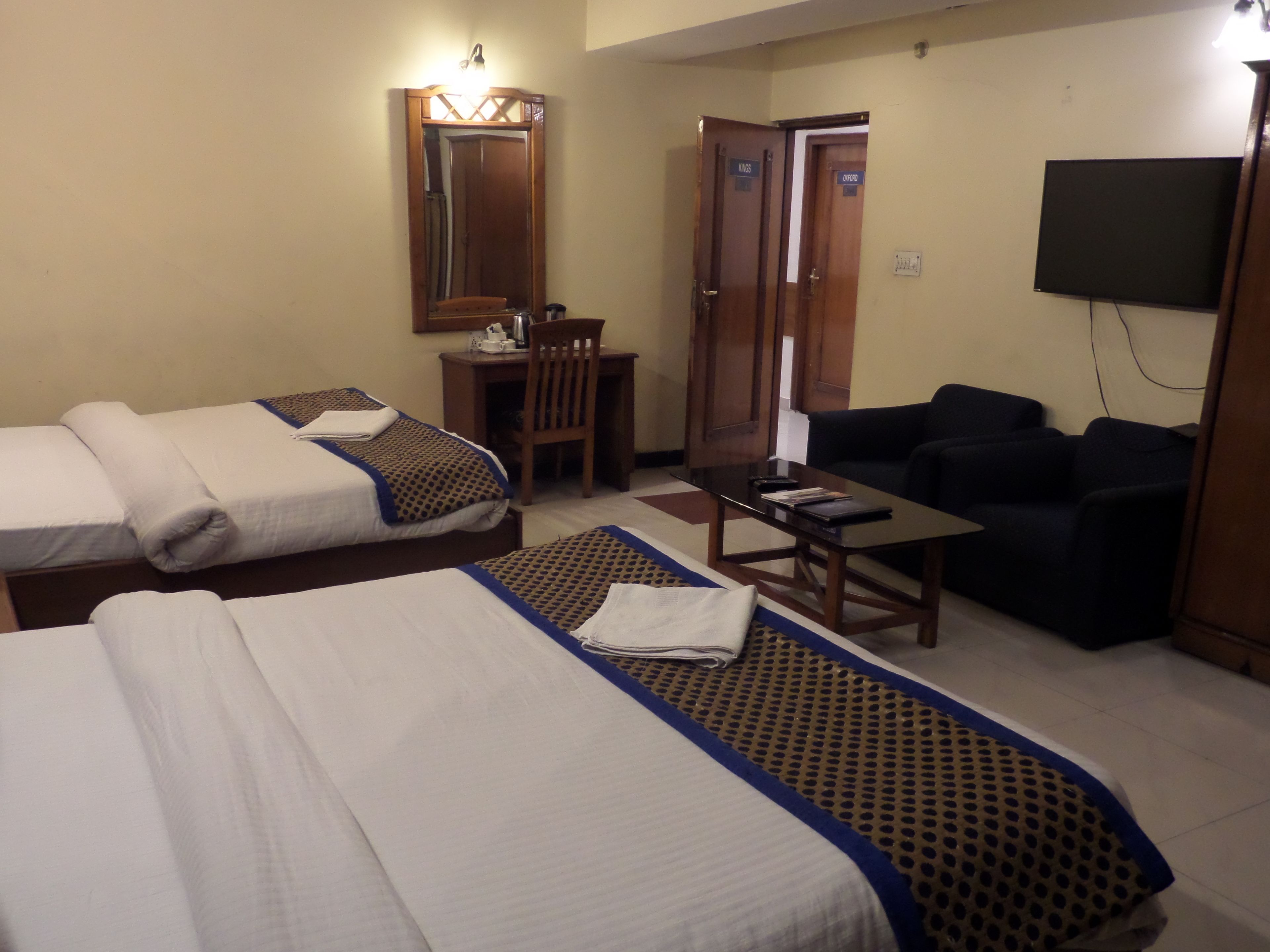 Habitación de hotel con dos camas, un escritorio, una silla, un sofá y un televisor.