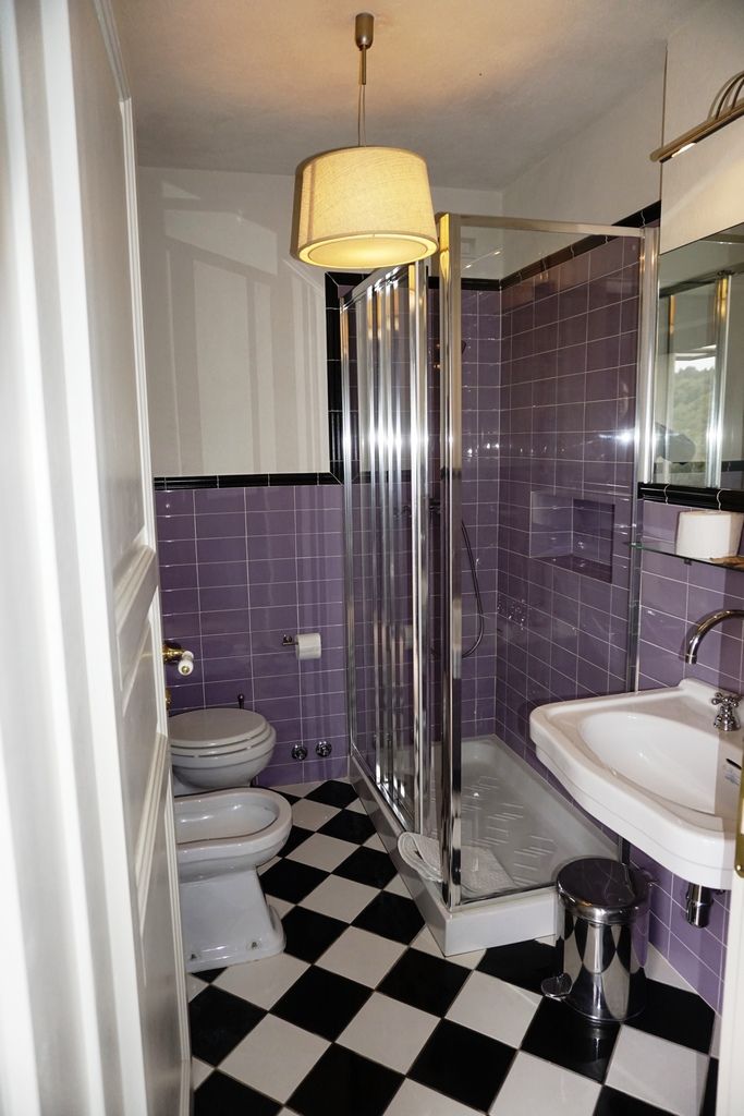 Ein Badezimmer mit Dusche, Toilette, Waschbecken und einem Schachbrettboden.
