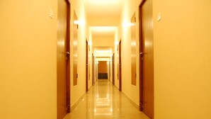 A long, narrow hallway with wooden doors on both sides, leading to a staircase at the end. - Raahat Inn Kodaikanal (Kodaikanal)